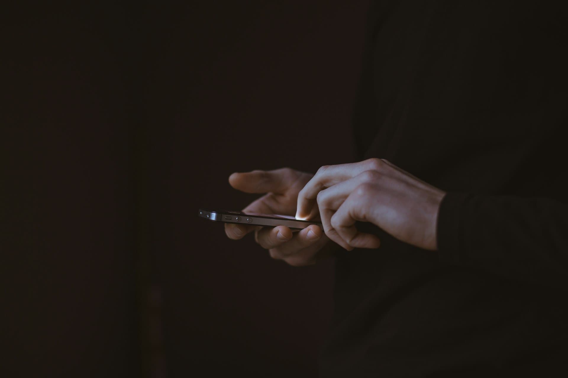 Hands using a smartphone in the dark